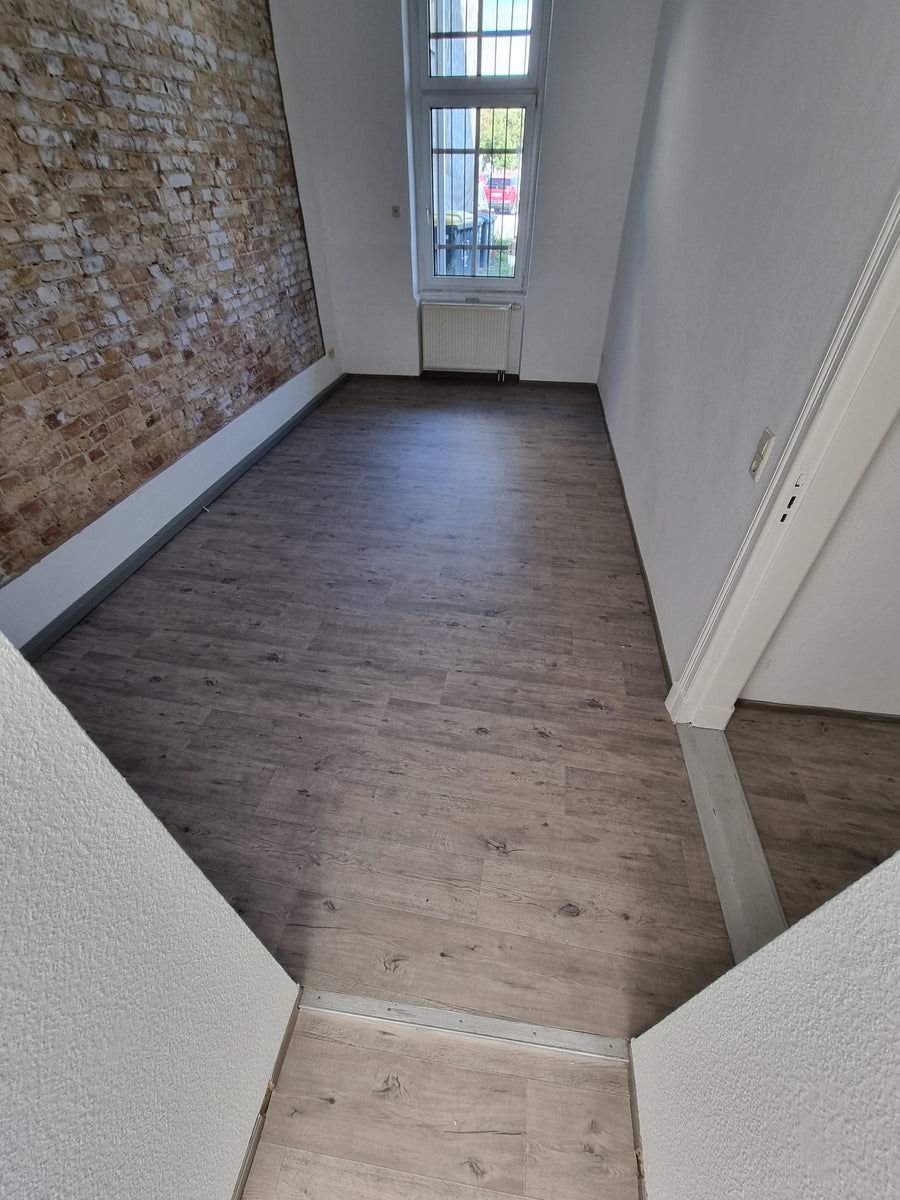 Altbauzimmer mit Ziegelwand und neuem Vinylboden nach der Renovierung