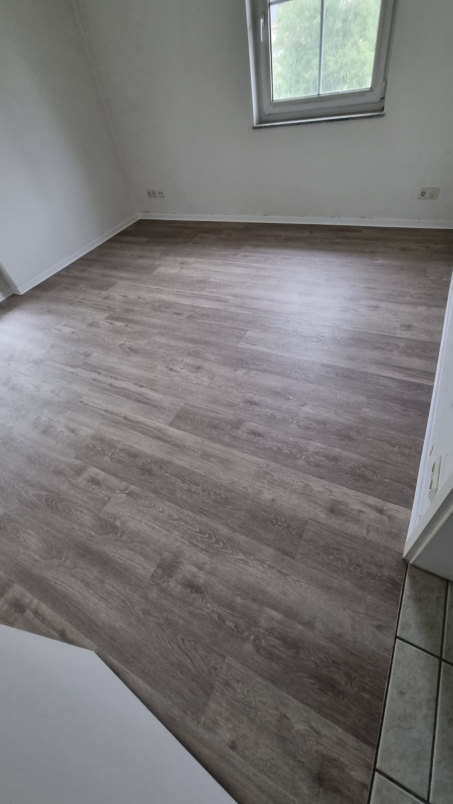 Zimmer mit grauem Vinylboden in Holzoptik nach der Verlegung